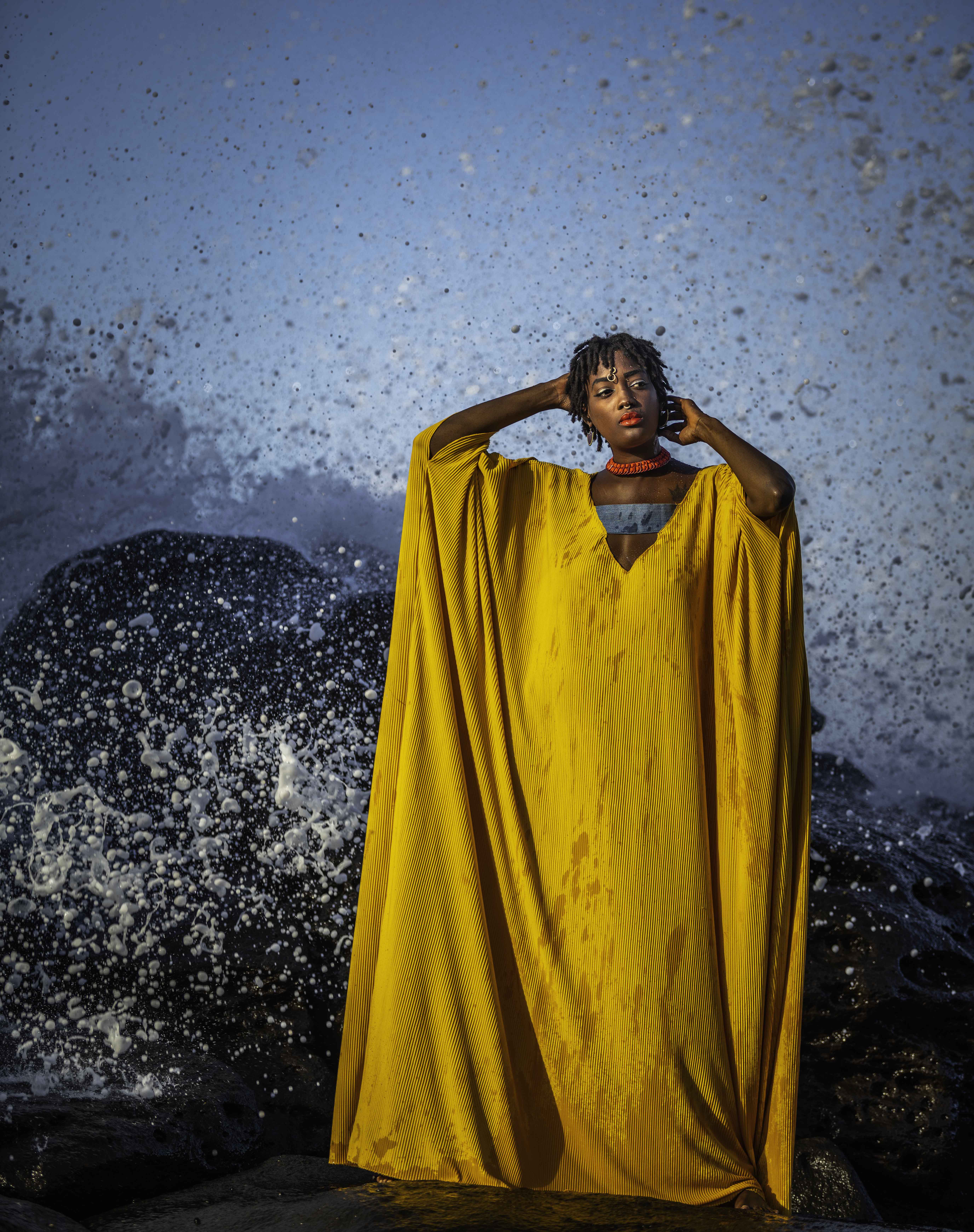 Model poses against crashing waves, Dakar