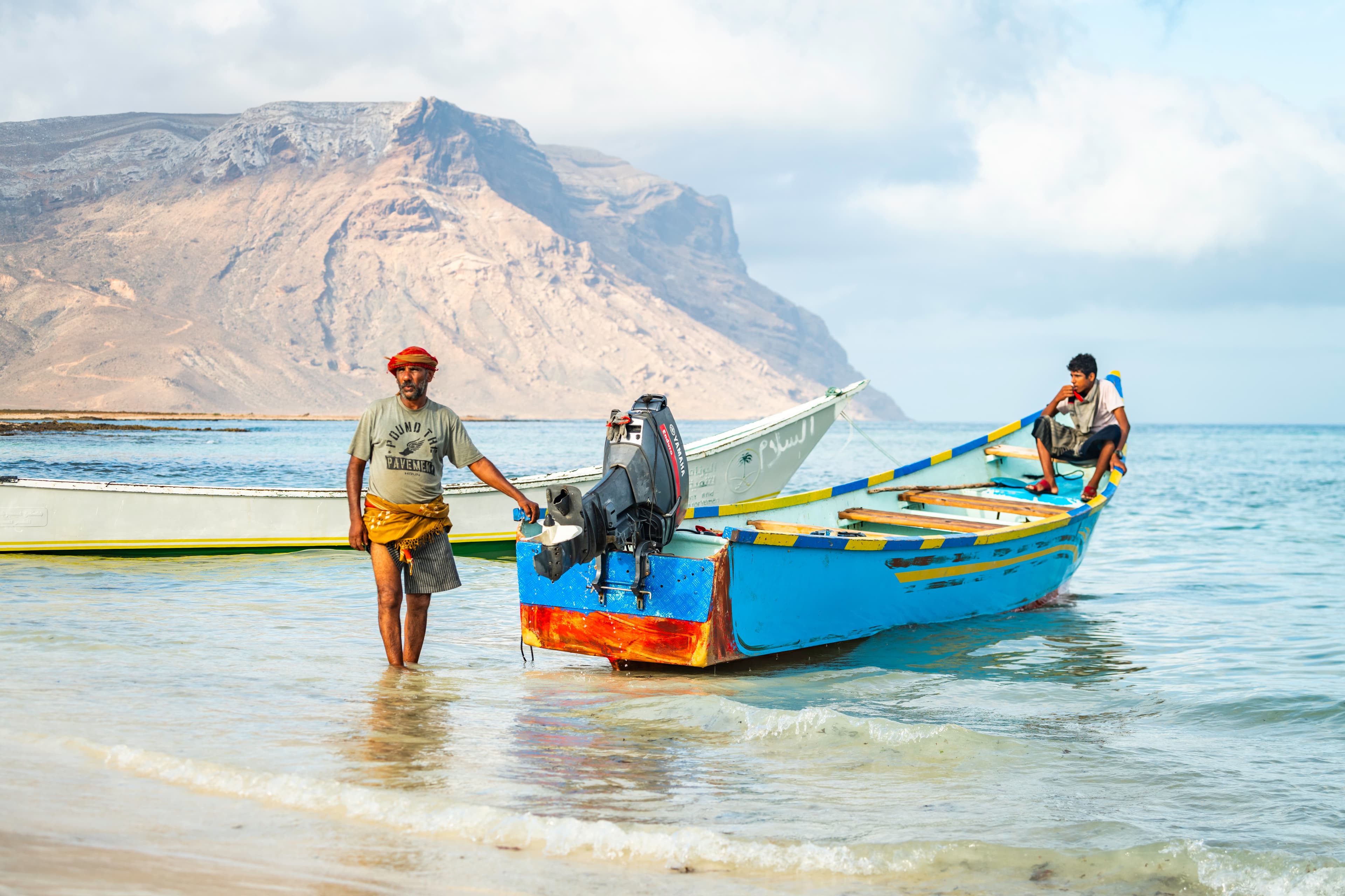 Fishermen with boats on sandy shore, Socotra