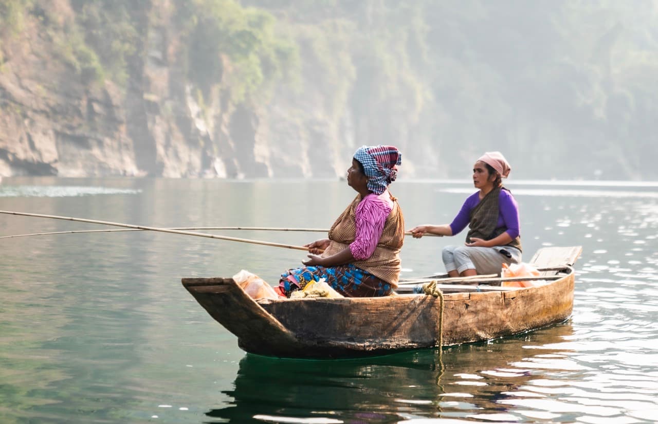 Women fishing on calm river, Meghalaya